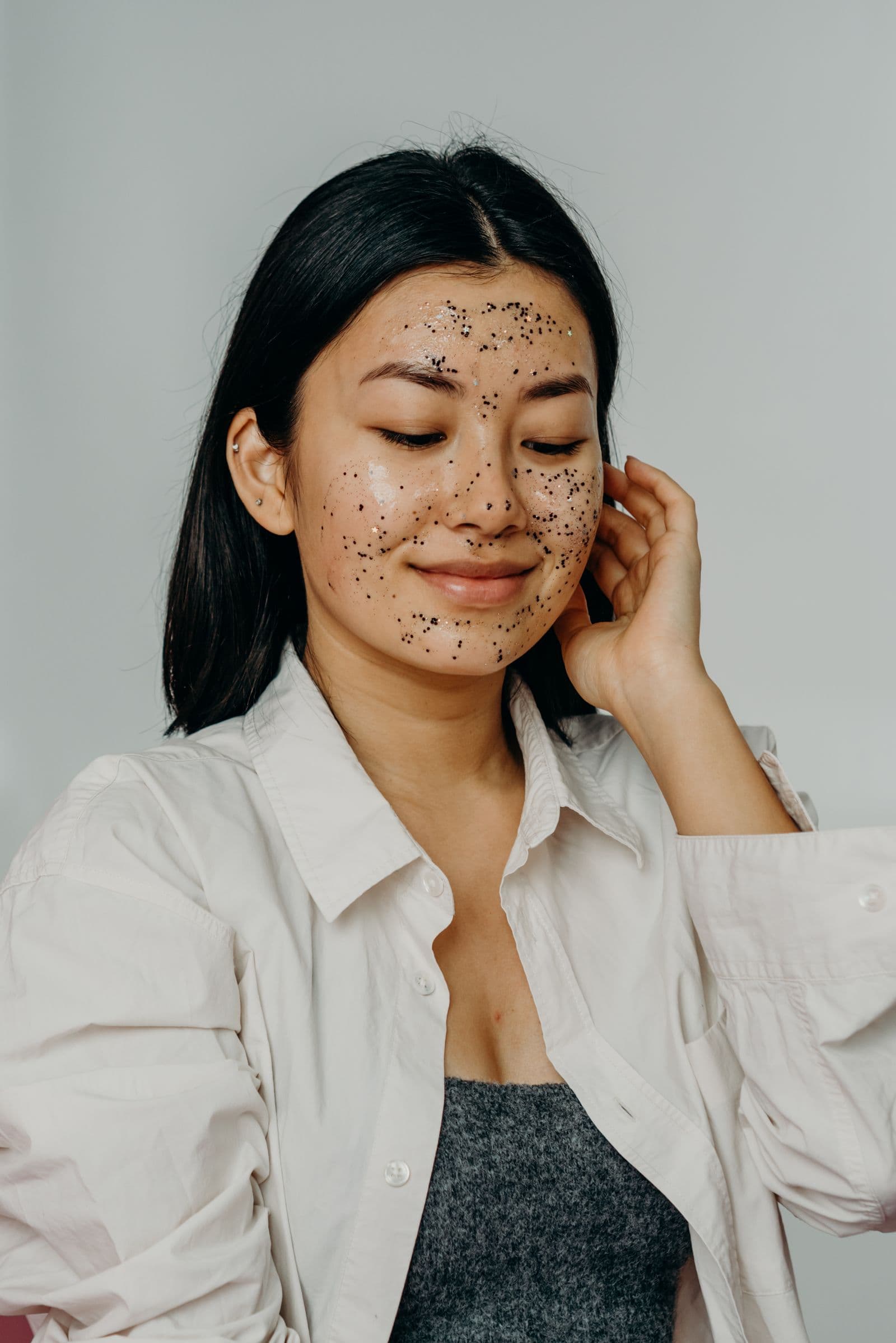 A young woman with a glittery facial mask, smiling